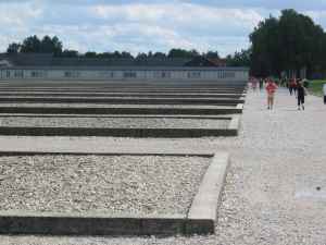 Dachau concentration camp. Concrete frames mark the site of former barracks, like the ones in the distance.